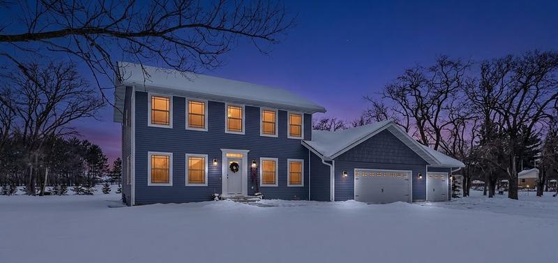 A Minnesota home at dusk in the snow, every window lit