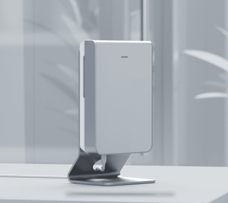 A UniFi In-Wall HD access point standing on a small metal desk stand, with its network cable running out the back