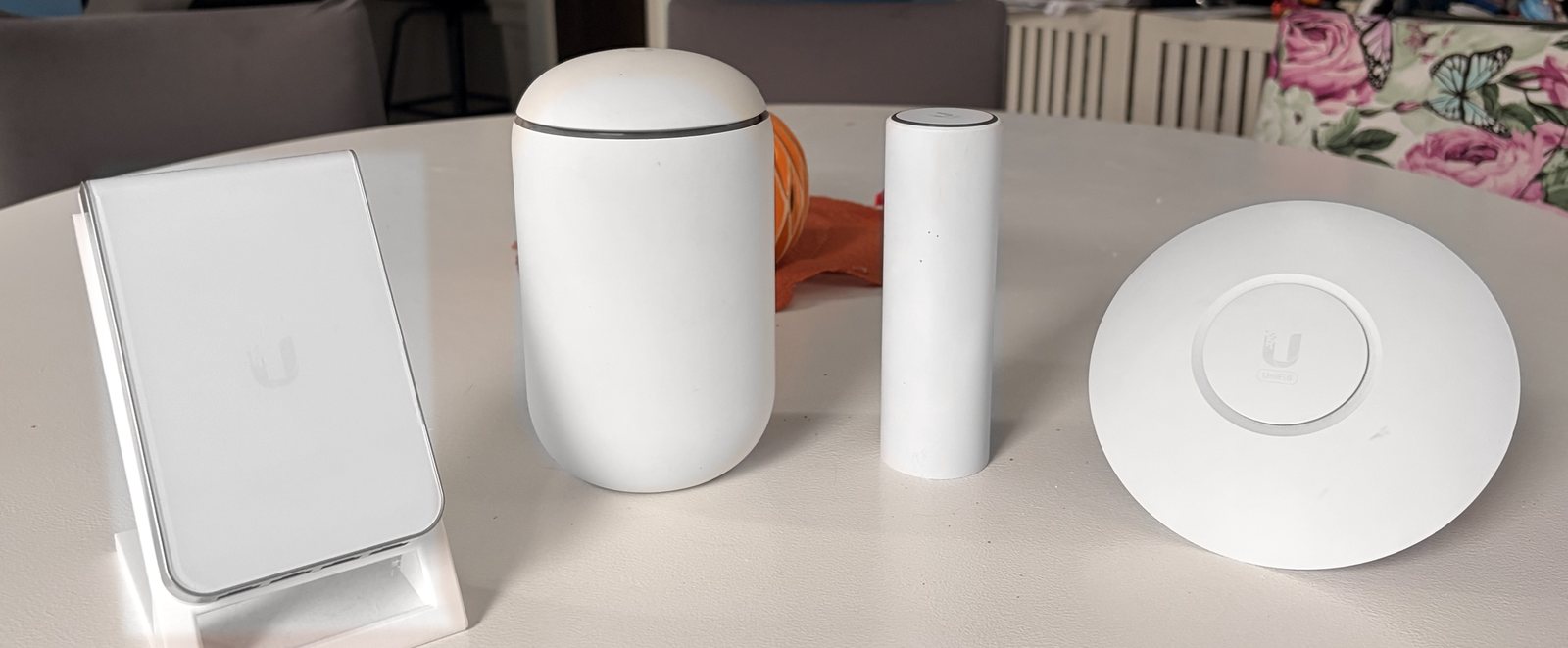 The same four white devices on a kitchen table in a real home
